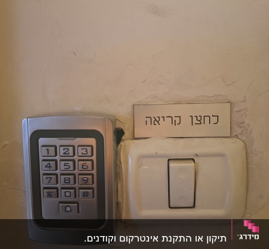 לוח מקשים ומתג על קיר עם שלט